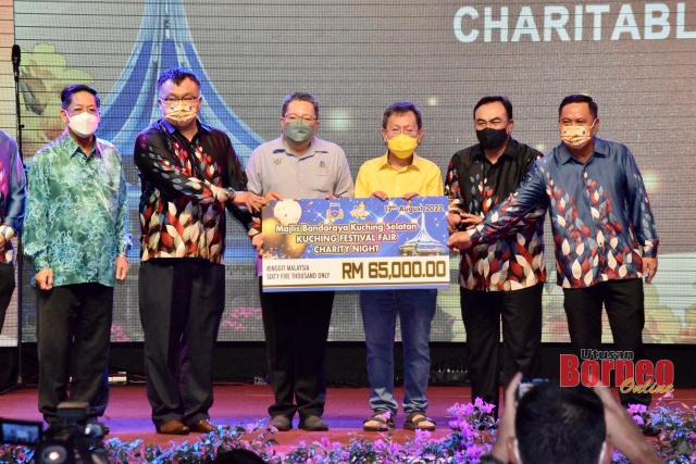 Pengerusi Penganjur Festival Kuching 2022, Goh Tze Hui (dua kiri) secara simbolik menyerahkan sumbangan RM65,000 kepada Datuk Bandar Majlis Bandaraya Kuching Selatan (MBKS) Dato Wee Hong Seng (tiga kiri). Turut kelihatan Dr Sim (tiga kanan). - Gambar Roystein Emmor