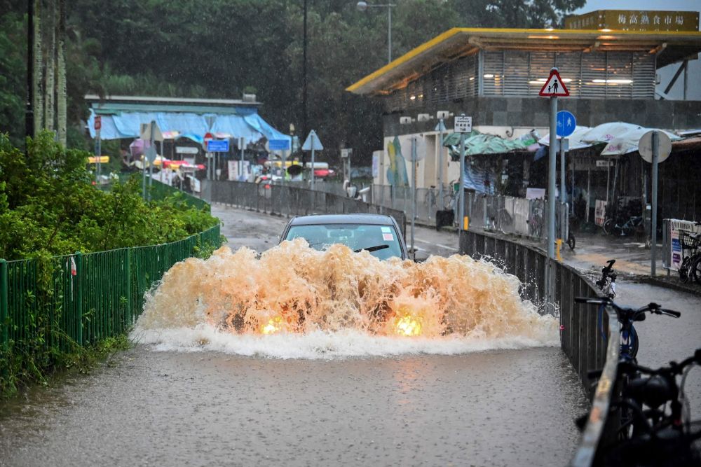 Sebuah kereta dilihat melalui jalan raya yang dilanda banjir selepas hujan lebat di Pulau Lantau di Hong Kong semalam. — Gambar AFP