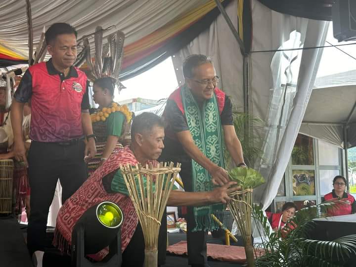 Mong (kanan) meletakkan piring di atas tabak buluh sambil diperhatikan Langgong (kiri) semasa merasmikan majlis berkenaan.