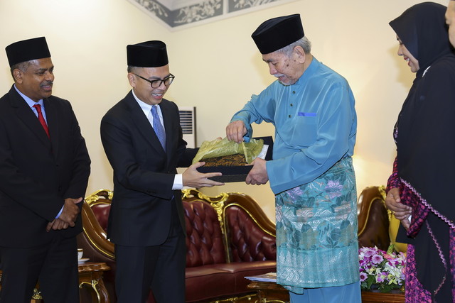 Tun Wan Junaidi (dua, kanan) menerima cenderamata daripada Fahmi (dua, kiri) di Astana Negeri di Petra Jaya hari ini. - Gambar BERNAMA