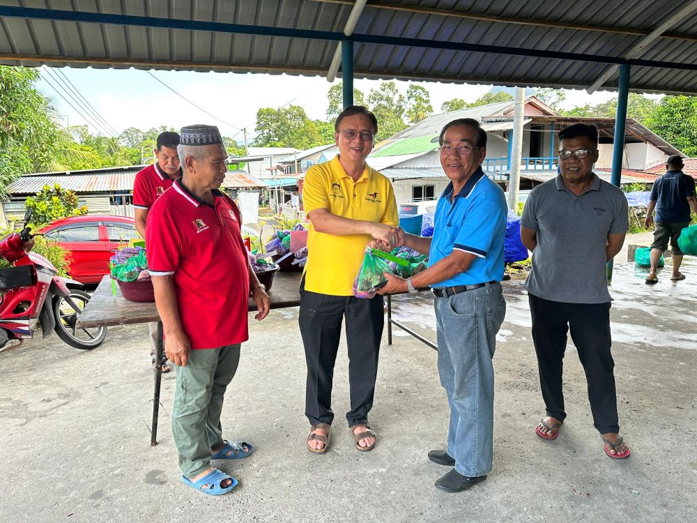 Lo (tengah) menyampaikan sumbangan kepada salah seorang penerima daging korban sempena sambutan Hari Raya Aidiladha hari ini.