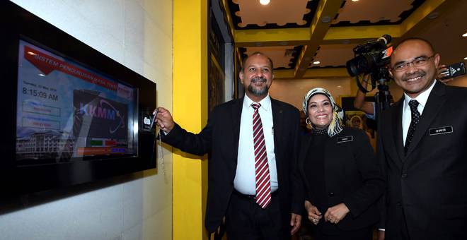 PIKUL TUGAS: Gobind mengimbas kad pada mesin perakam waktu elektronik pada hari pertama masuk ke pejabat Kementerian Komunikasi dan Multimedia Malaysia (KKMM) untuk memulakan tugas sebagai menteri yang baharu semalam. Turut hadir Dr Sharifah (dua kiri) dan Shakib (kanan). — Gambar Bernama