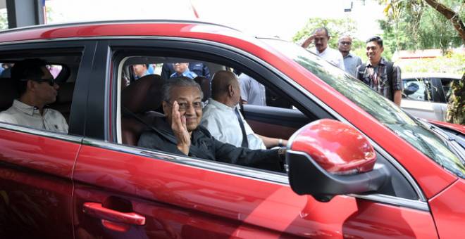 Dr Mahathir Mohamad memandu sendiri kenderaan jenis Proton X70 sambil melambai tangan kepada kakitangan pejabat daerah selepas menghadiri Taklimat Pembangunan Pulau Langkawi di Pejabat Daerah dan Tanah Langkawi hari ini. - Gambar Bernama 