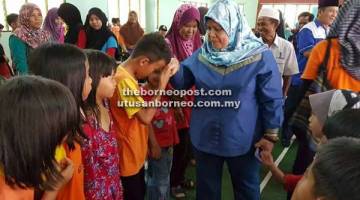 MESRA: Rubiah bersalaman dengan kanak-kanak yang hadir pada Program Mesra Rakyat di Dewan Masyarakat Kampung Tanjong Apong, Asajaya kelmarin.