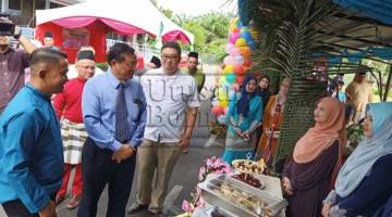 Dr Teo ditemani Giri (belakang berbaju Melayu) melawat gerai makanan semasa Gawai Raya di Wisma Persekutuan Lopeng.